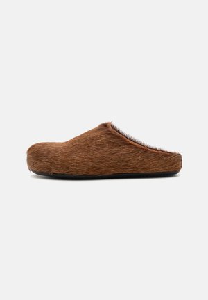 Pantofole in pelliccia marrone con punta arrotondata, texture morbida e schiena bassa. Presentano una suola in gomma nera per aderenza e durata.