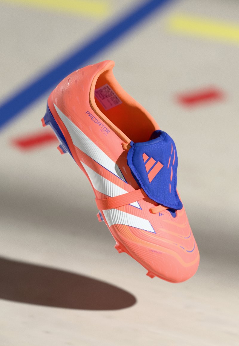 Chuteira de futebol laranja brilhante com accents azuis e riscas brancas. Apresenta um cabedal texturizado e um colar em estilo meia para um ajuste seguro.