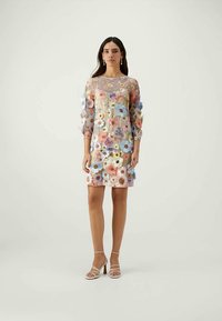 Vestido floral com mangas longas transparentes, apresentando flores em tons de rosa, azul e roxo sobre um fundo claro. Corte até ao joelho com um ajuste descontraído.