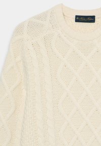 Kremowy sweter z dzianiną w splot warkoczowy z diamentowymi wzorami, ściągaczem przy dekolcie i fakturowanym wykończeniem tkaniny.