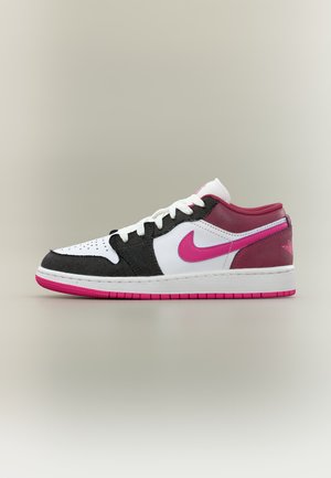 Baskets basses avec panneaux noirs, blancs et rouge foncé, logo Nike rose vif et détails sur la semelle, lacets blancs sur fond neutre.