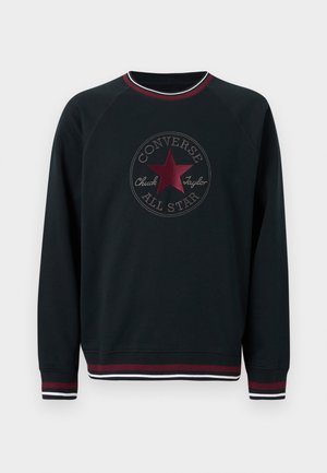 Svart langermet crewneck-genser med burgunder stjerne og "Converse All Star Chuck Taylor"-logo, med burgunder og hvitt stripet kantbånd.