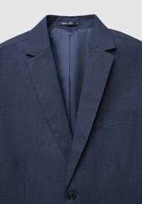 Blazer blu navy realizzato in tessuto testurizzato con un leggero motivo a quadri; presenta rever a punta, chiusura con un singolo bottone e taschino sul petto.