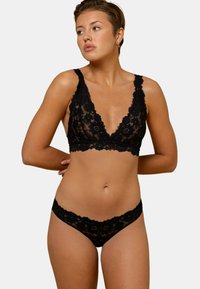Ensemble de bralette en dentelle noire avec culotte assortie. Comprend un motif floral, des bords festonnés et un décolleté en V profond pour un look délicat.