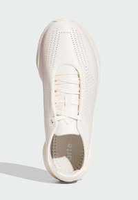 Chaussure de sport blanche avec un dessus perforé, un bout arrondi, des lacets élastiques et une semelle texturée. Présente une finition lisse et un design minimalist.