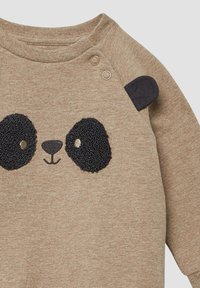 Beige Babystrampler mit einem schwarzen, strukturierten Panda-Gesicht und zwei Druckknöpfen am Ausschnitt, ausgestattet mit einem kleinen Stoffohr an einer Schulter.