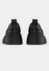 Svarte platåsneakers med glatt skinnoverdel, forsterket hæl og vevd detalj på baksiden, med en robust gummisåle.