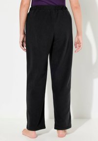 Zwarte fleece broeken met een elastische tailleband, een relaxte pasvorm en rechte pijpen, zonder zichtbare zakken of sluitingen. Glad materiaal.
