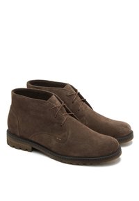 Brązowe zamszowe botki za kostkę z wiązaniem, okrągłym noskiem i teksturowaną powierzchnią. Posiadają ciemną gumową podeszwę z subtelnym wzorem bieżnika.