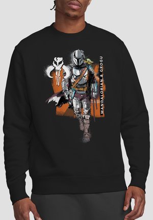 Schwarzer Sweatshirt mit Mandalorian in Rüstung, der mit Grogu auf der Schulter läuft, orangefarbener Hintergrund und weißer Text "MANDALORIAN & GROGU."