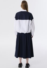 Robe color block bleu marine et blanche avec une coupe décontractée, une taille élastique et de longues manches. Finition en coton lisse.