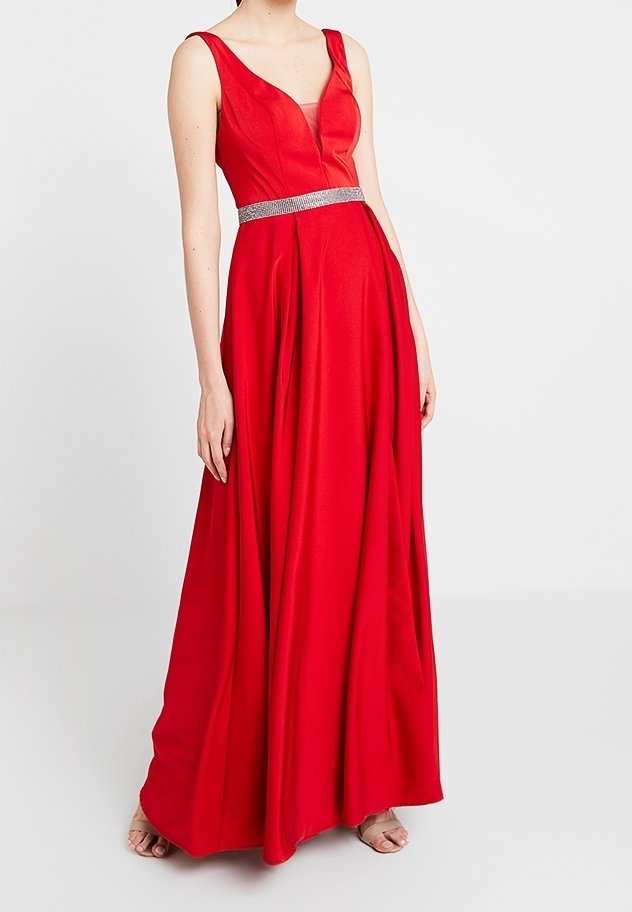 Robe rouge sans manches longue jusqu'au sol avec un décolleté en V profond et une ceinture argentée, portée par une personne debout devant un fond clair uni.