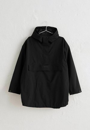 Sort hættetrøje regnjakke med frontklaplomme, trykknapslukning på krave og manchetter, hængende på en hvid vægkrog.