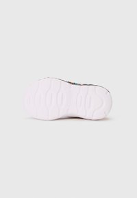 Sola de um sapatênis Skechers multicolorido com sola de borracha texturizada branca, exibindo o nome da marca em relevo no centro.