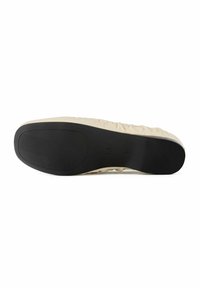 Beige shoe with a smooth, textured upper and a black rubber outsole featuring ridges for traction. Size and model details embossed on the sole.