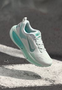 Leichte Laufschuhe mit einem weißen Mesh-Obermaterial, aqua Akzenten und strukturiertem Sohlenprofil. Verfügt über Schnürsenkel und eine gepolsterte Zwischensohle zur Unterstützung.
