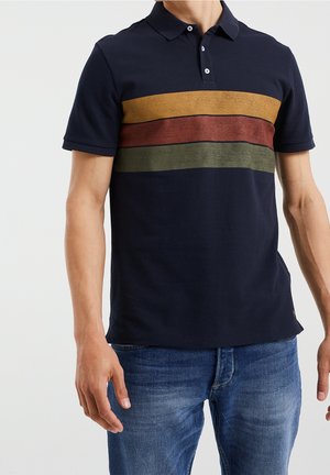 Polo bleu marine avec un col classique, présentant des rayures horizontales en or, rouge et vert. Texture douce, manches courtes et coupe ajustée.