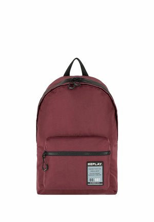 Bordeauxfarbener Rucksack mit schwarzen Reißverschlüssen, Fronttasche, Obergriff und einem Etikett mit der Aufschrift "REPLAY" sowie Produktdetails auf der Fronttasche.