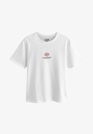 Balta medvilninė marškinė su raudonu ir žaliu tekstu, kuriuose užrašyta "ASAHIKAWA" ir "Hokkaido" po sudėtingo gėlių dizaino priekyje.