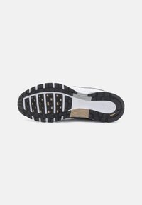 Semelle d'une basket Nike blanche et noire avec une surface texturée et le logo Nike visible sur la zone du talon, présentée sur un fond blanc.