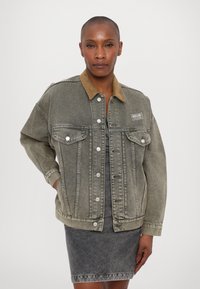 Denim jacket featuring a faded gray color, corduroy collar, two chest pockets, and silver snap buttons; relaxed fit with visible stitching.
