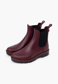 Bottes Chelsea imperméables bordeaux avec des côtés élastiques noirs texturés, des languettes de traction et une semelle noire robuste avec des accents de couture bruns.