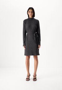 Kullsvart strikket kjole med høy hals, lange ermer og belted midje. Glatt tekstur, kne-lengde hem og minimalistisk design.