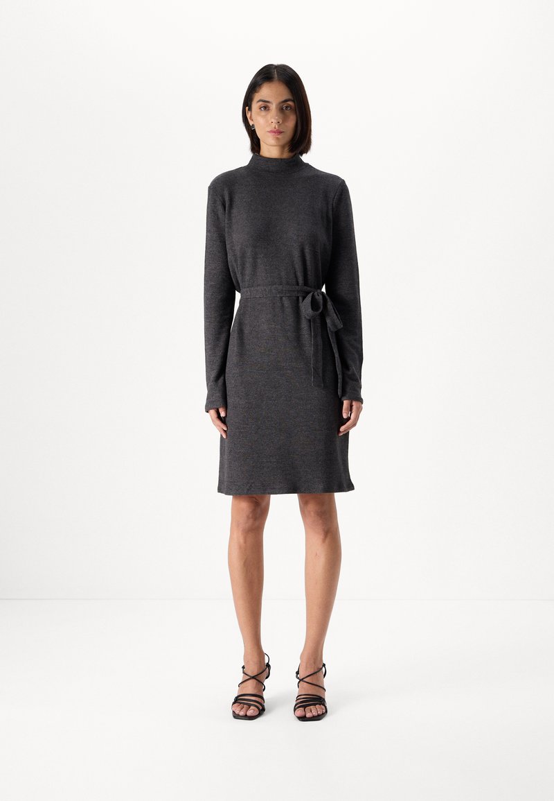 Kullsvart strikket kjole med høy hals, lange ermer og belted midje. Glatt tekstur, kne-lengde hem og minimalistisk design.