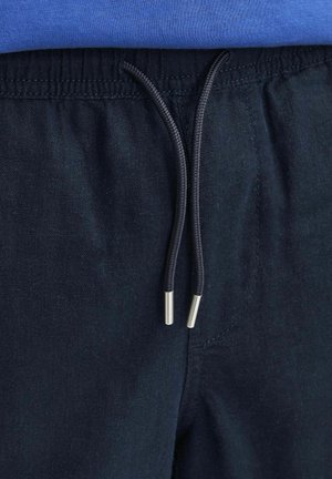 Pantaloni della tuta blu navy con tessuto testurizzato, dotati di una vita elastica e di lacci scuri con punte metalliche argentate.