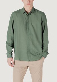Camicetta da uomo a maniche lunghe di colore verde tenue, realizzata in tessuto liscio. Presenta un colletto a punta, bottoni frontali e polsini con bottoni.