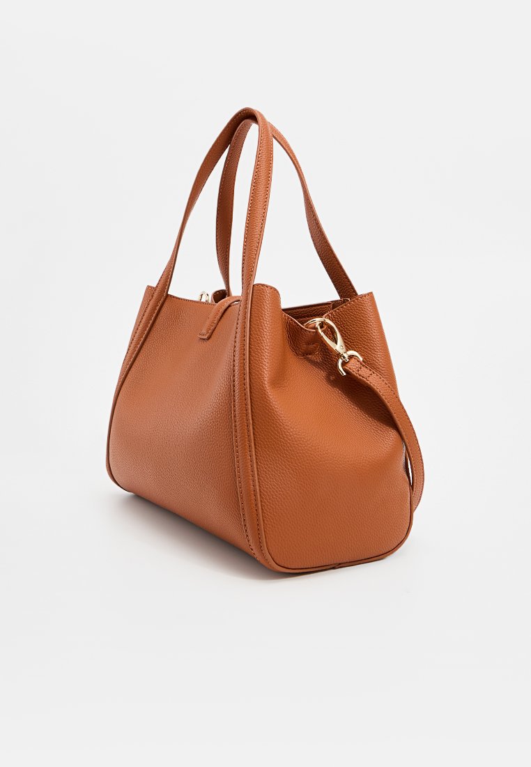 Sac à main en cuir brun à texture granuleuse avec double poignées et une bandoulière amovible, présentant un extérieur lisse et une forme arrondie.