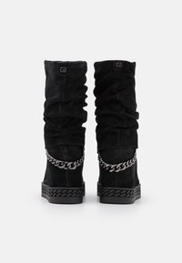 Černé semišové kozačky ke kolenům s nazýranou texturou, robustním řetízkovým detailem kolem kotníku a texturovanou gumovou podrážkou.