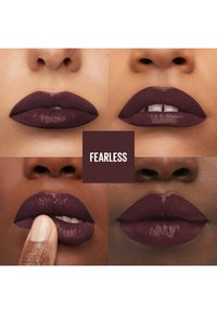 Rouge à lèvres prune profond sur des lèvres pulpeuses. Les textures varient entre mate et brillante. L'étiquette centrale indique "FEARLESS" sur un fond sombre.