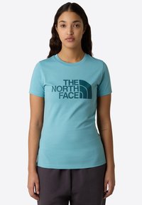 Lyseblå kortærmet t-shirt lavet af bomuld, med et stort mørkeblåt logo fra The North Face på forsiden. Rund udskæring.