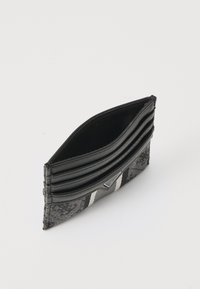 Portefeuille noir avec trois emplacements pour cartes, fabriqué en tissu texturé avec une surface à motif et un accent en logo argenté. Design plat et rectangulaire.