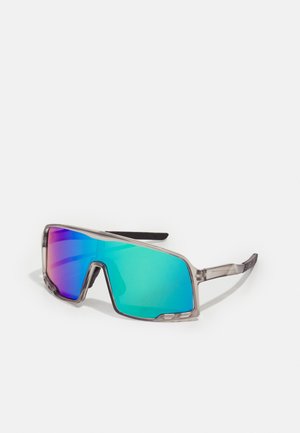 Lunettes de soleil avec une monture transparente, de grandes lentilles miroir affichant des dégradés de turquoise à violet, et des accents noirs texturés sur les branches.