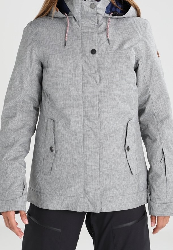 Veste à capuche gris clair avec boutons sur le devant, poches à rabat et poignets ajustables portée sur un pantalon noir.