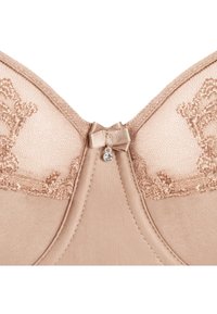 Beżowy biustonosz z koronkowymi zdobieniami na miseczkach, małą tkaninową kokardką i zawieszką z kryształków na środku przodu.