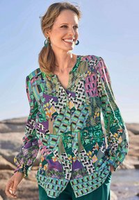 Blusa multicolore caratterizzata da un mix di motivi geometrici e floreali, chiusura a bottoni, maniche lunghe con polsini elasticizzati e scollatura a V.
