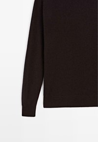 Maglione marrone a maniche lunghe realizzato in un tessuto morbido e testurizzato. Presenta un colletto rotondo e polsini a costine, con un design minimalista.