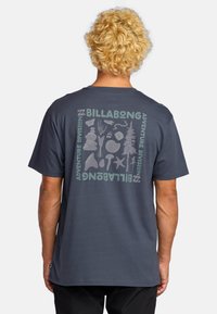 Navy blue short-sleeve t-shirt with a graphic print on the back featuring abstract nature-themed illustrations and "BILLABONG" text.