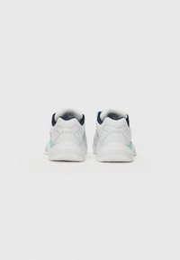 Białe buty sportowe z granatowymi akcentami, posiadające teksturowaną podeszwę oraz turkusowy detal po boku. Widoczne logo z tyłu.