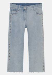 Calças de ganga azul claro com um design cropped de perna larga. Apresenta detalhes de tachas metálicas prateadas nas costuras laterais e uma bainha desfiada.