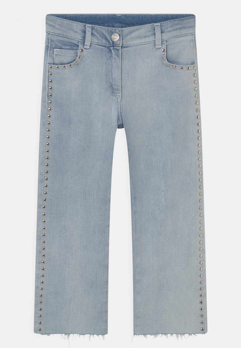 Calças de ganga azul claro com um design cropped de perna larga. Apresenta detalhes de tachas metálicas prateadas nas costuras laterais e uma bainha desfiada.