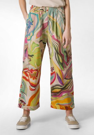 Wijdvallende, meerkleurige broek met abstracte patronen, elastische tailleband en opgerolde boorden, gemaakt van lichtgewicht stof. Gecombineerd met beige sneakers.