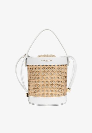 Petit sac seau avec corps en rotin tressé beige, garniture en cuir blanc, poignée supérieure, sangle réglable et fermeture à cordon de serrage en tissu.