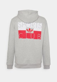 Grå huvtröja med huva, prydd med en röd och vit grafik från en sportklubb samt en broderad röd Adidas-logotyp. Mjuk bomullsblandning.