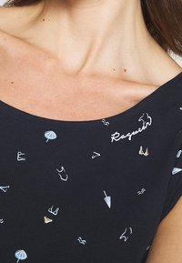 Granatowa bluzka z dekoltem łódkowym, ozdobiona rozproszoną haftem przedstawiającym parasole i kostiumy kąpielowe w jasno niebieskich, złotych i białych nitkach.