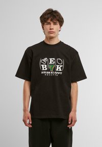 Sort bomulds t-shirt med rund halsudskæring, korte ærmer, og frontgrafik med "BIS ES KLAPPT RECORDS" samt stiliserede elementer i grøn og hvid.