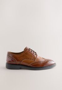 Chaussure habillée brogue marron en cuir pour homme avec semelle noire et perforations décoratives, vue de profil sur un fond uni.
